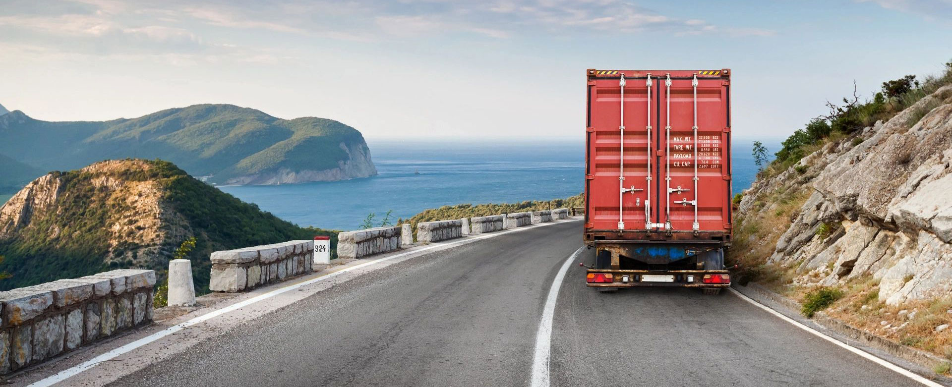 Cargo truck on the mountain highway with blue sky and sea on a background